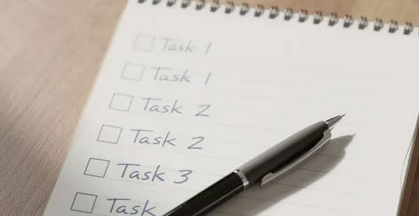 A notepad with a checklist sits next to a calculator on a wooden desk, creating a tidy workspace ideal for planning or managing finances. This setup may be useful for those exploring online casinos and evaluating deposit bonus offers or calculating potential winnings from casino games.