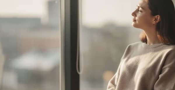 A calm person is sitting by a window, enjoying a moment of relaxation as natural light fills the space. This serene setting evokes a sense of peace, reminiscent of the atmosphere found in the best online casinos where one can unwind while playing real money casino games.